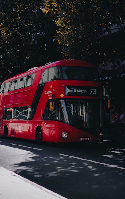 A bright red double-decker bus, number 73, displaying the destination 'Stoke Newington' on the front, is stopped on a city street. The bus features a modern, smooth exterior with large windows and a b
